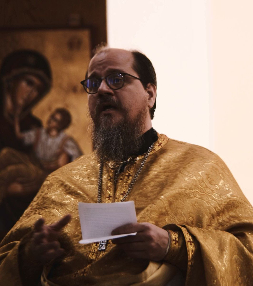 Father John reads out loud from his notes